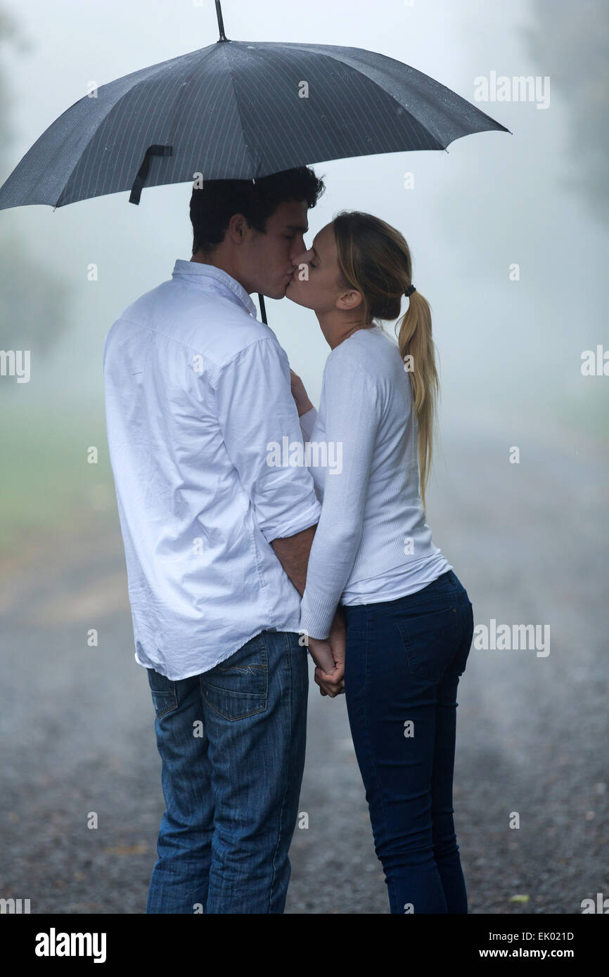 boyfriend and girlfriend kissing under umbrella in the rain Stock Photo -  Alamy