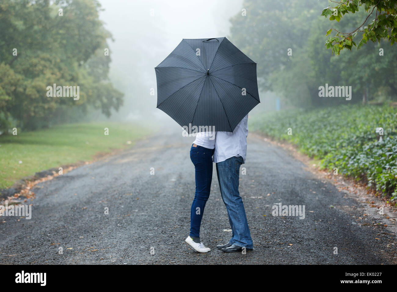 couple kissing behind the umbrella in the mist Stock Photo
