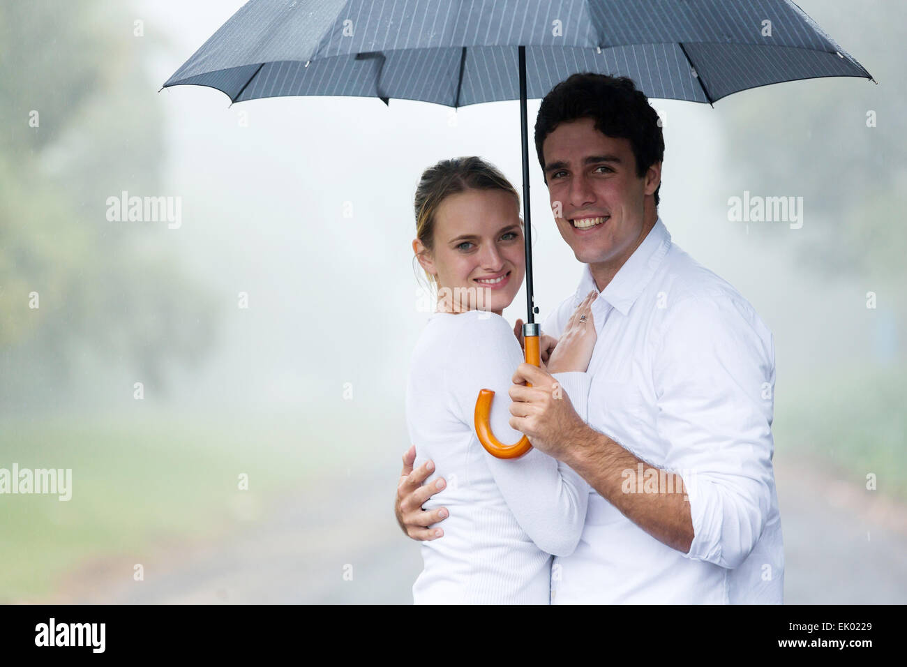 happy young couple holding an umbrella in the rain Stock Photo