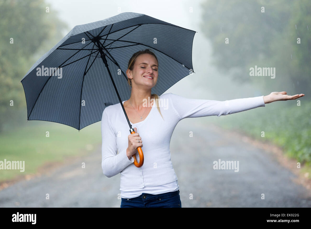 attractive woman with umbrella enjoying the rain Stock Photo