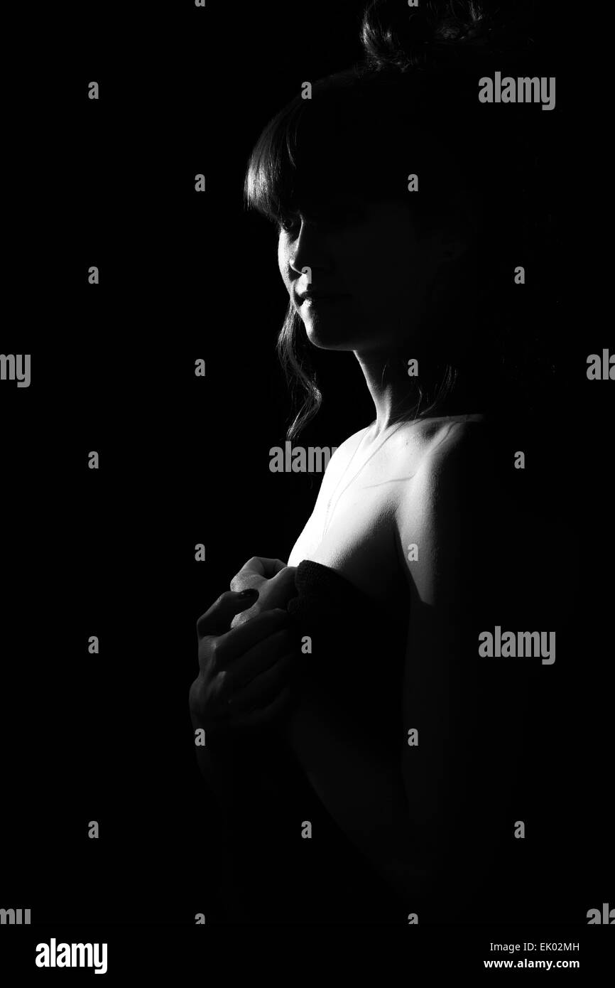 A high key, black & white silhouette of a tall woman model isolated on a black and black background. Stock Photo
