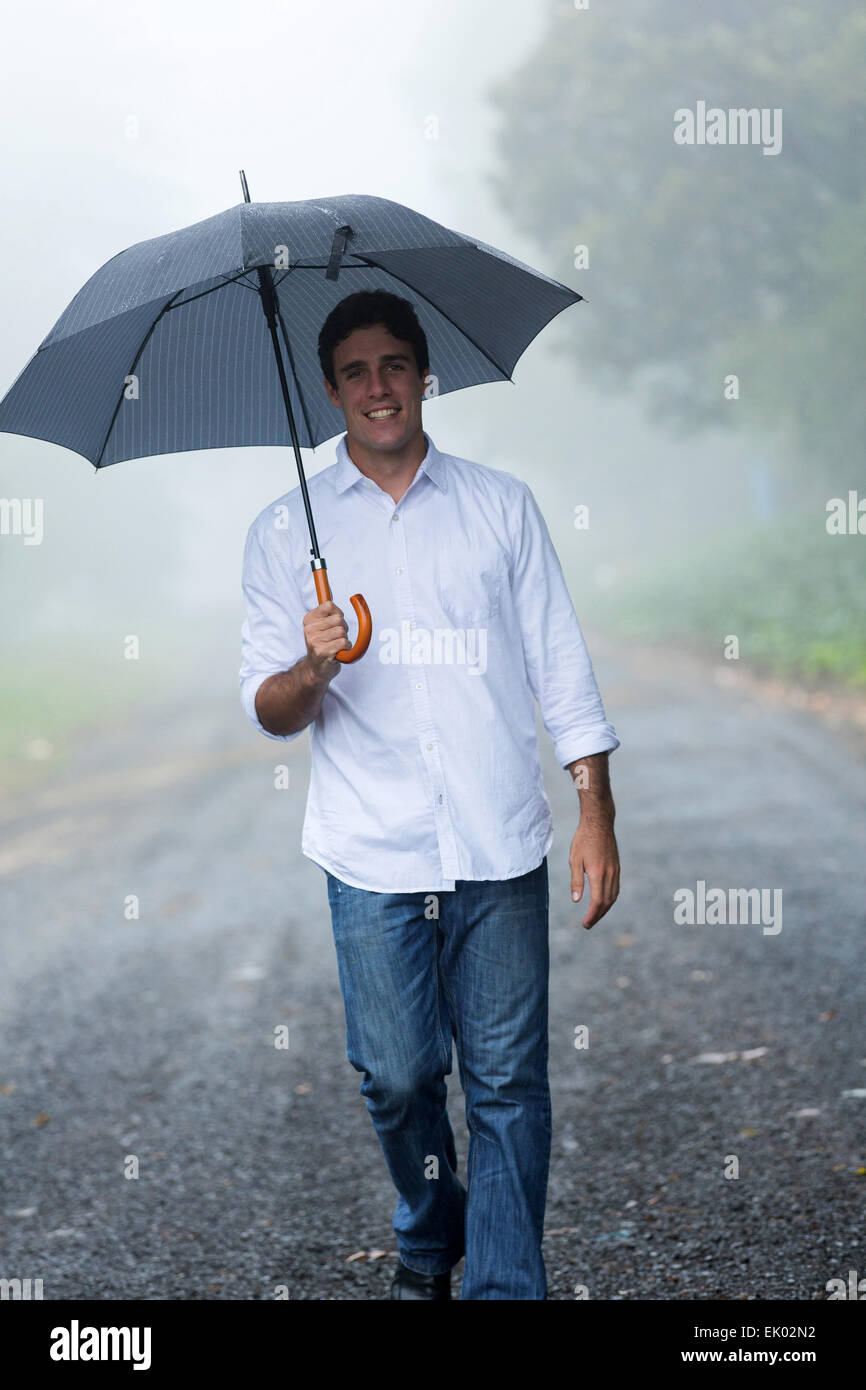 happy man with umbrella walking in the rain Stock Photo