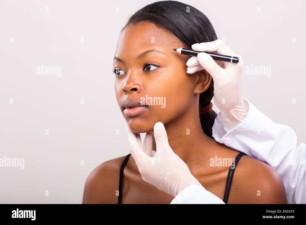 doctor drawing correcting lines African girl face before plastic surgery Stock Photo