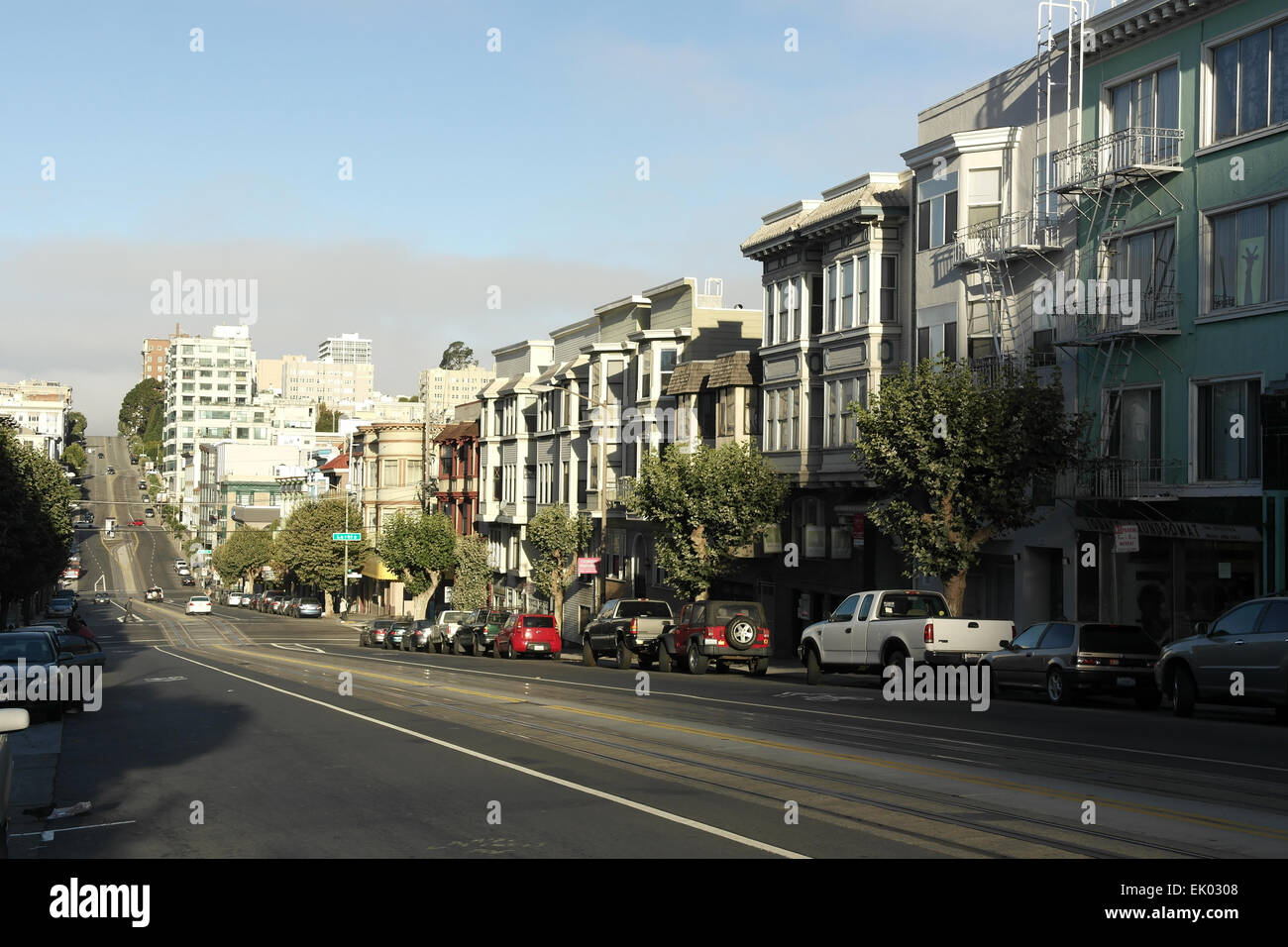Blue sky sunny view parked cars, buildings California Street descending incline to Larkin, Polk Streets, Nob Hill, San Francisco Stock Photo