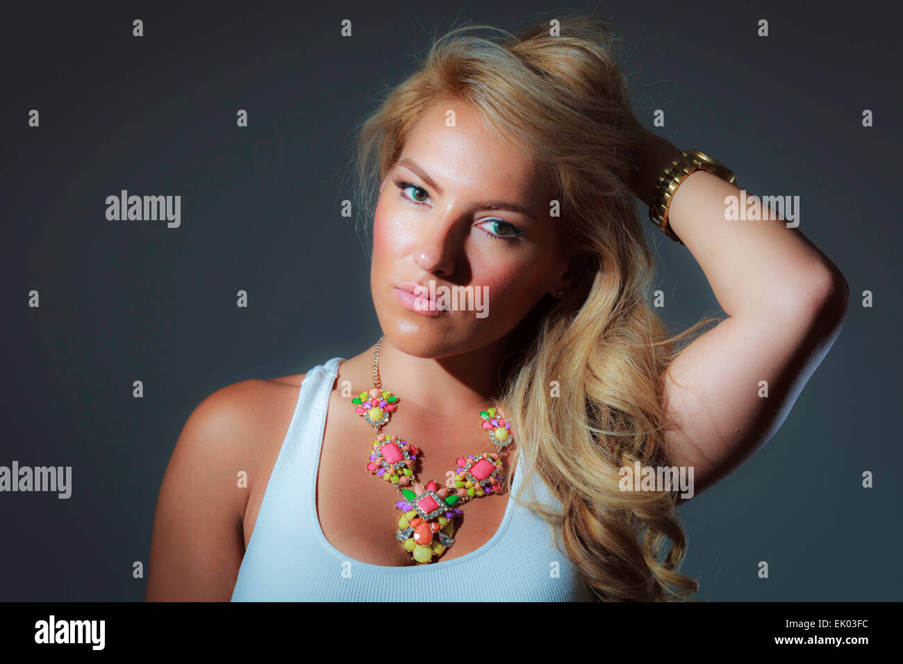 A blonde latina girl in a blue tank top and a big colorful necklace. Stock Photo