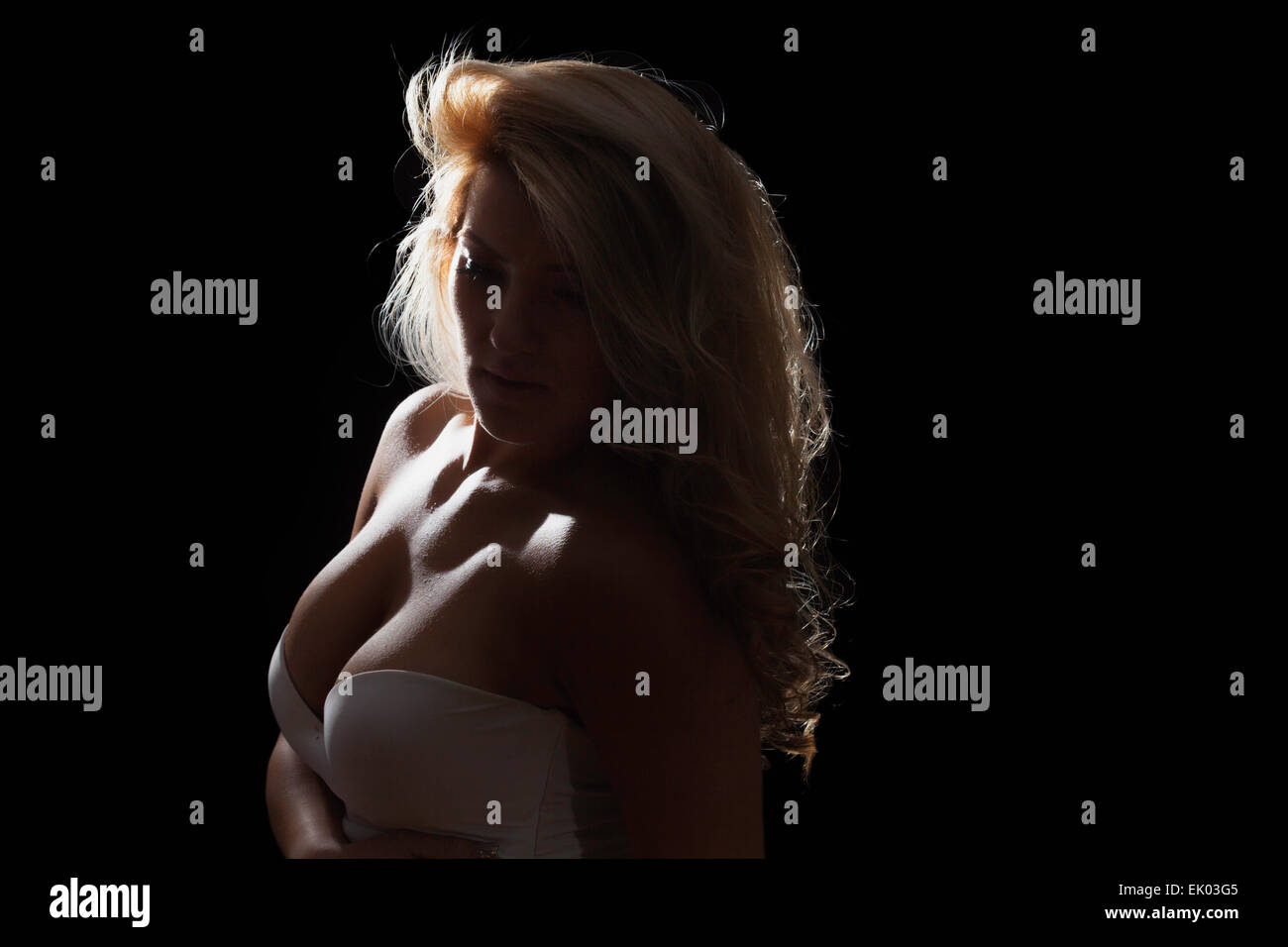 A blonde latina model isolated on black background. Dark and moody low-key. Stock Photo