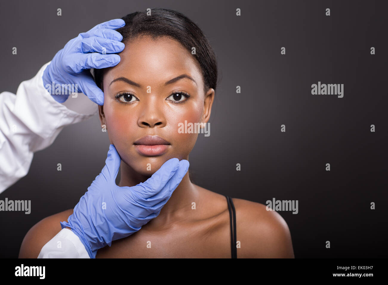 dermatologist checking pretty African woman face skin Stock Photo
