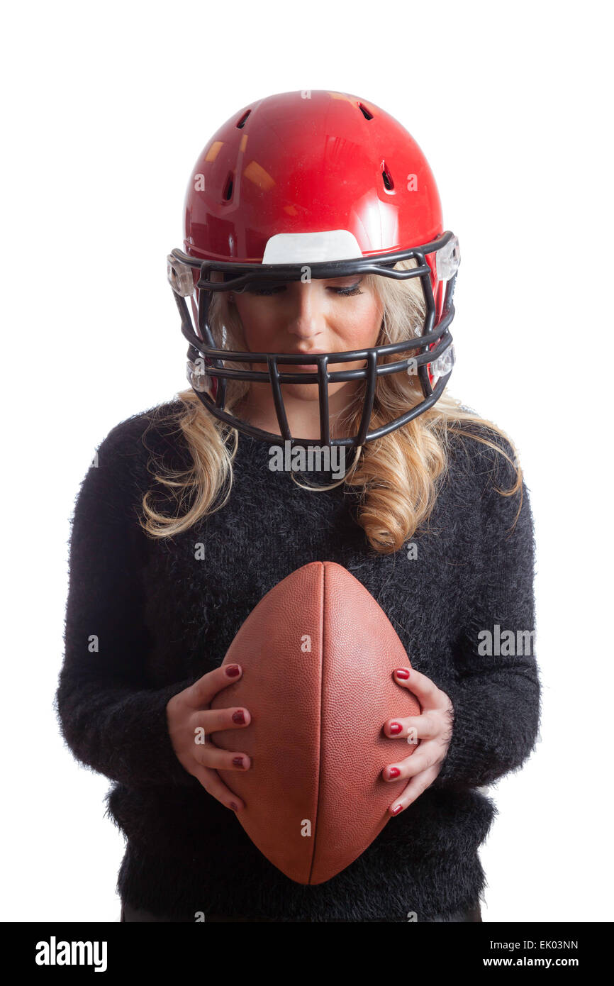 A pretty, Latina, blonde wearing a red football helmet and holding a football and looking down. Isolated on white background. Stock Photo