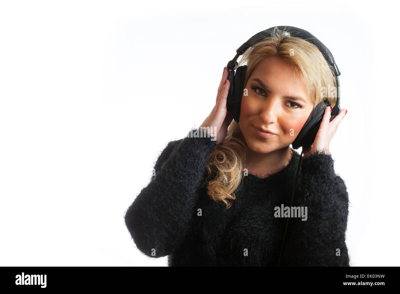 A pretty, blonde, Latina girl wearing large studio headphones and listening to music. Isolated on white background. Stock Photo