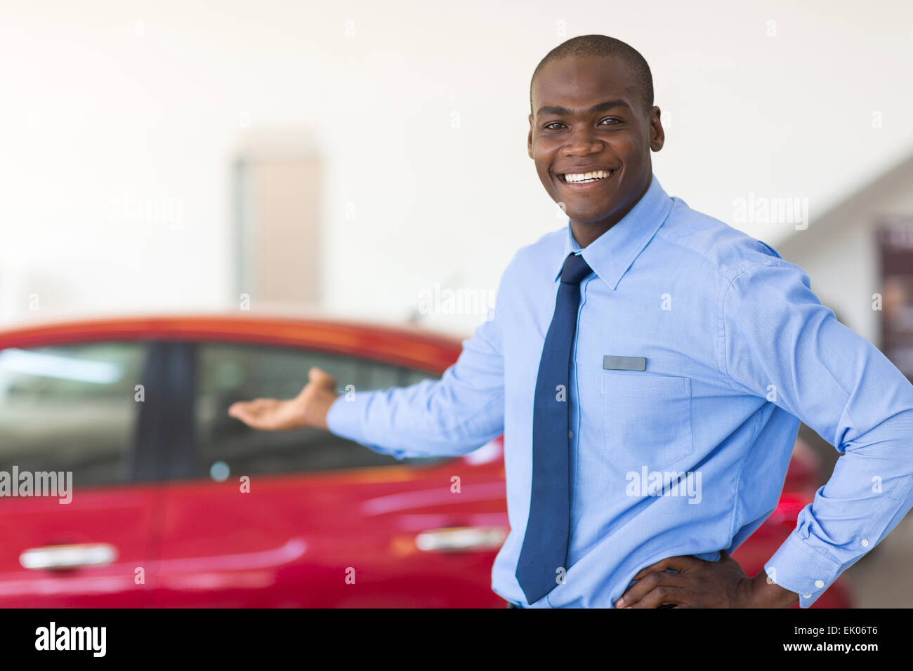 African car salesman standing at showroom presenting new cars Stock Photo