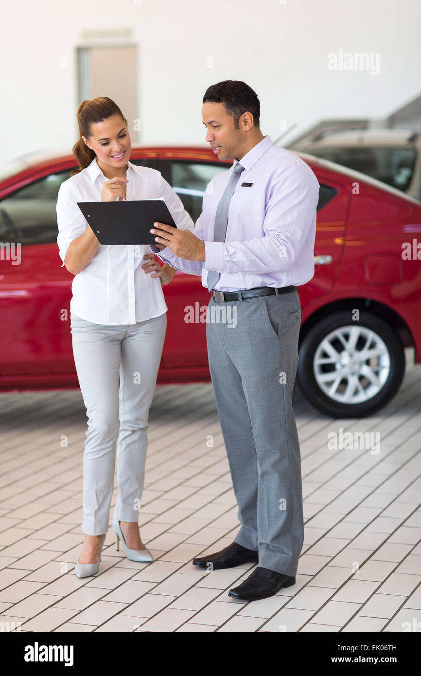 car dealer explaining sales contract to young woman buying a car Stock Photo