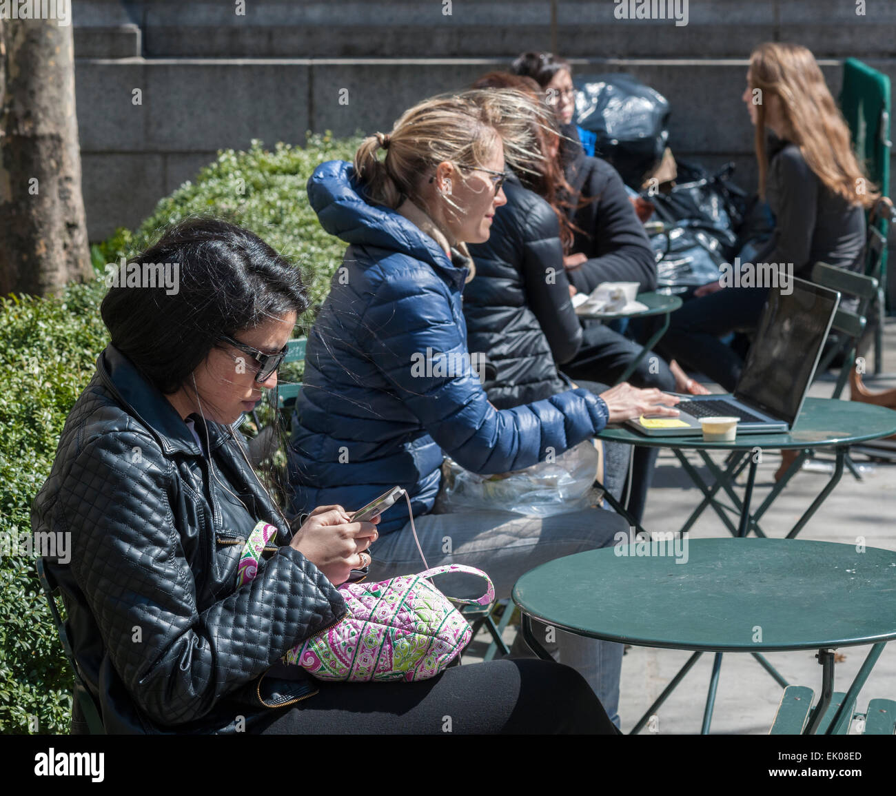 New Yorkers and visitors use their electronic devices as they shed the winter blues in Bryant Park in New York on Thursday, April 2, 2015. Warm weather in the mid 60's attracted office workers and tourists to the outdoors. (© Richard B. Levine) Stock Photo