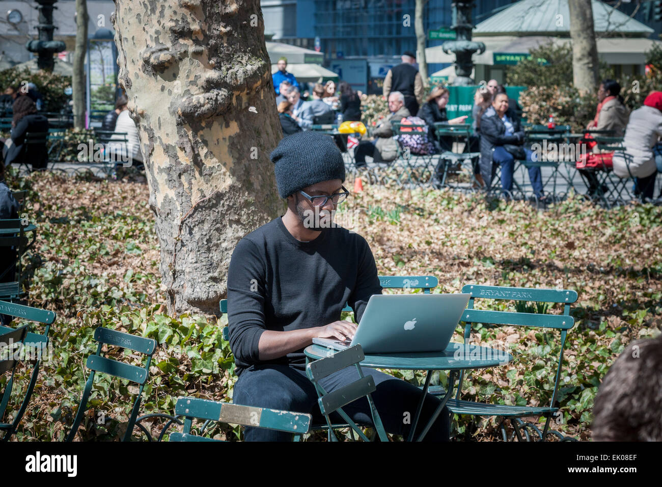 A man uses his MacBook, joining other park goers shedding the winter blues in Bryant Park in New York on Thursday, April 2, 2015. Warm weather in the mid 60's attracted office workers and tourists to the outdoors. (© Richard B. Levine) Stock Photo