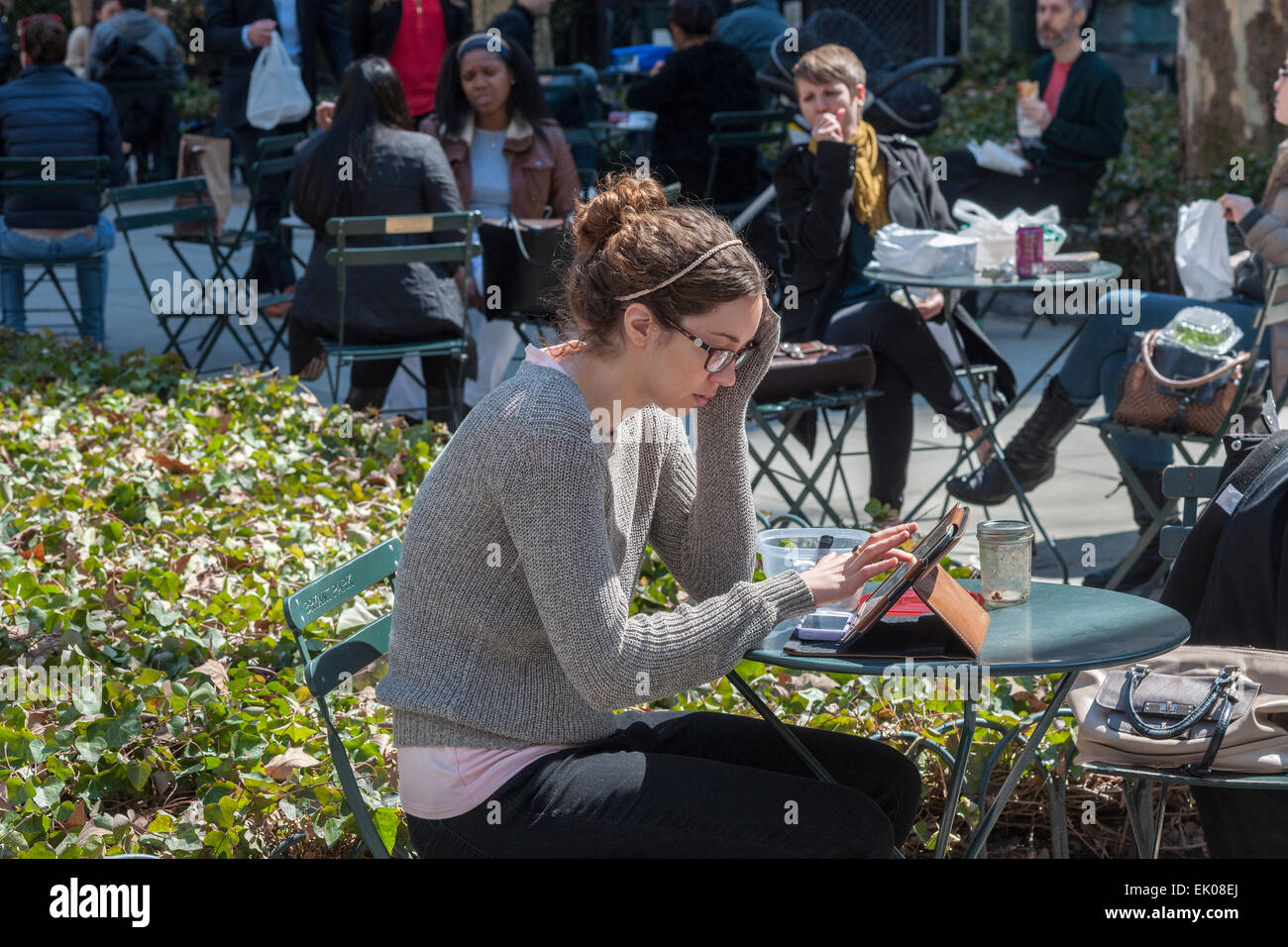 A woman uses he iPad, joining other park goers shedding the winter blues in Bryant Park in New York on Thursday, April 2, 2015. Warm weather in the mid 60's attracted office workers and tourists to the outdoors. (© Richard B. Levine) Stock Photo