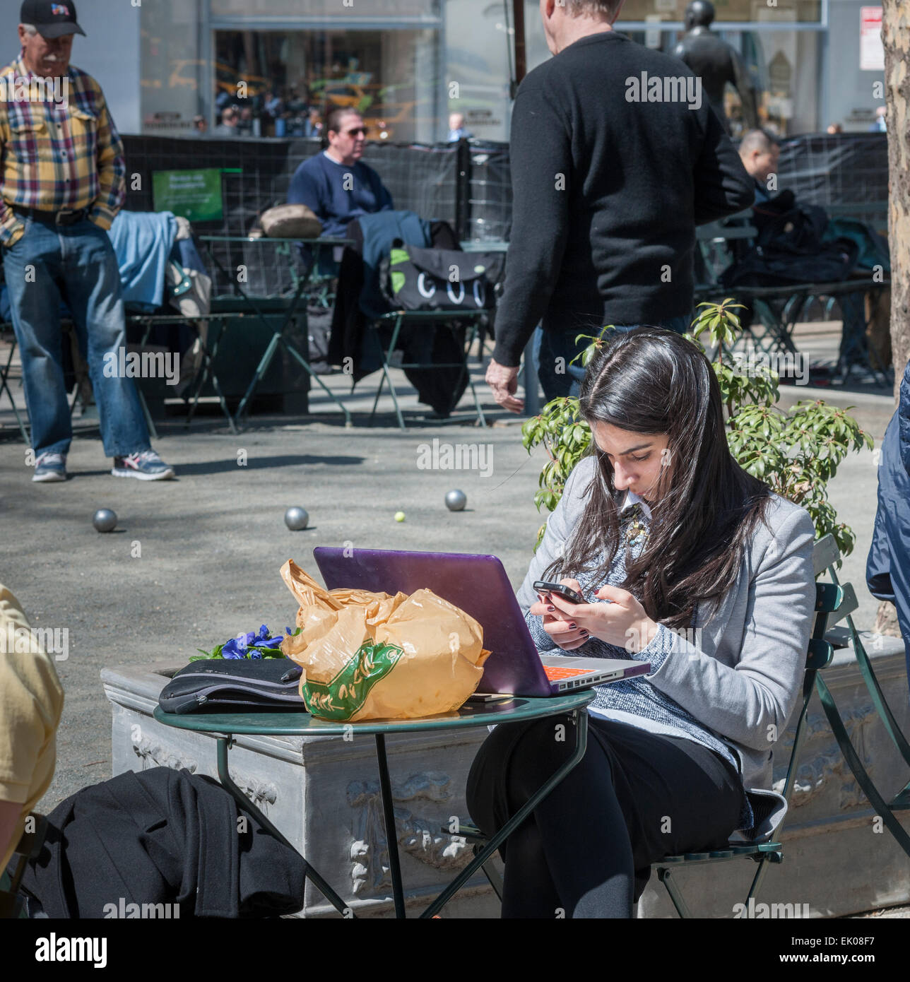 A woman with her smartphone and laptop, joining other park goers shedding the winter blues in Bryant Park in New York on Thursday, April 2, 2015. Warm weather in the mid 60's attracted office workers and tourists to the outdoors. (© Richard B. Levine) Stock Photo