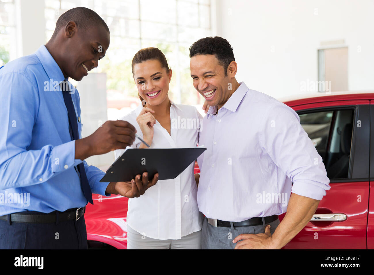 African car dealer explaining sales contract to couple buying a car Stock Photo
