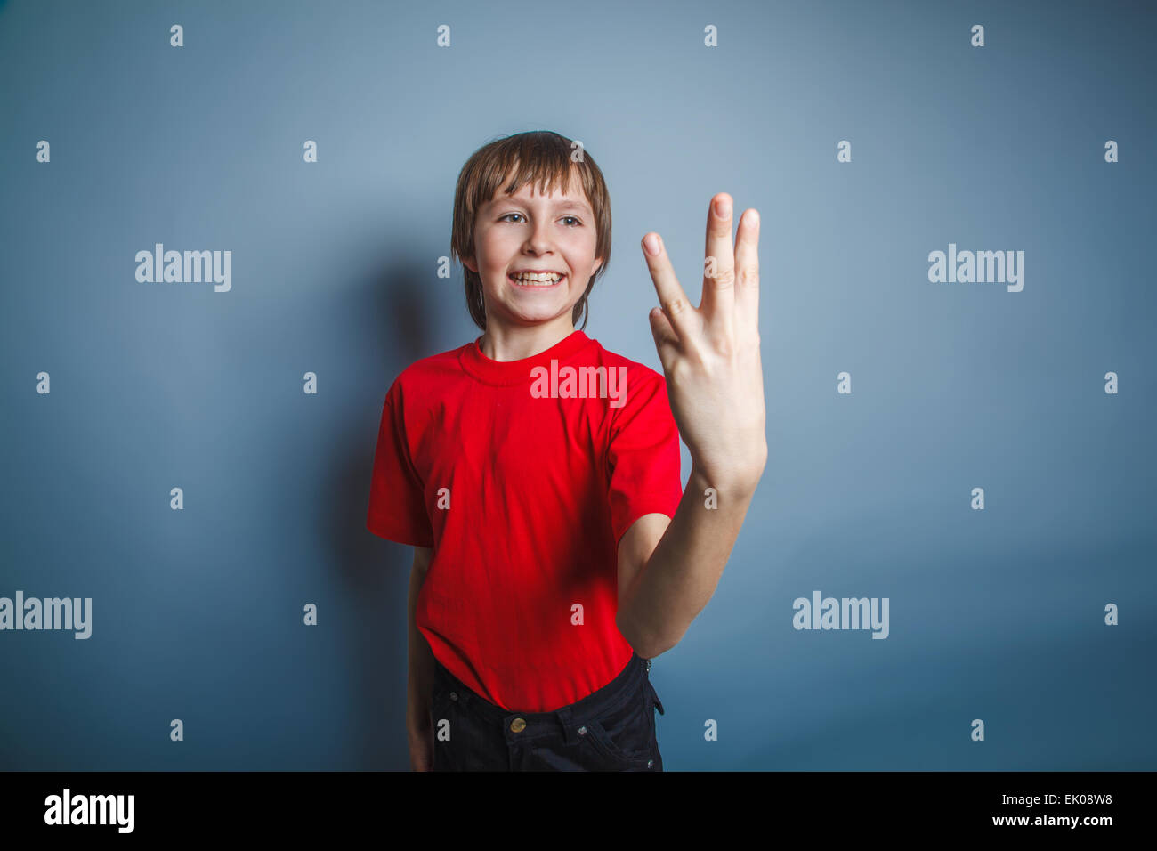 teenager boy brown European appearance in a red shirt shows thre Stock Photo