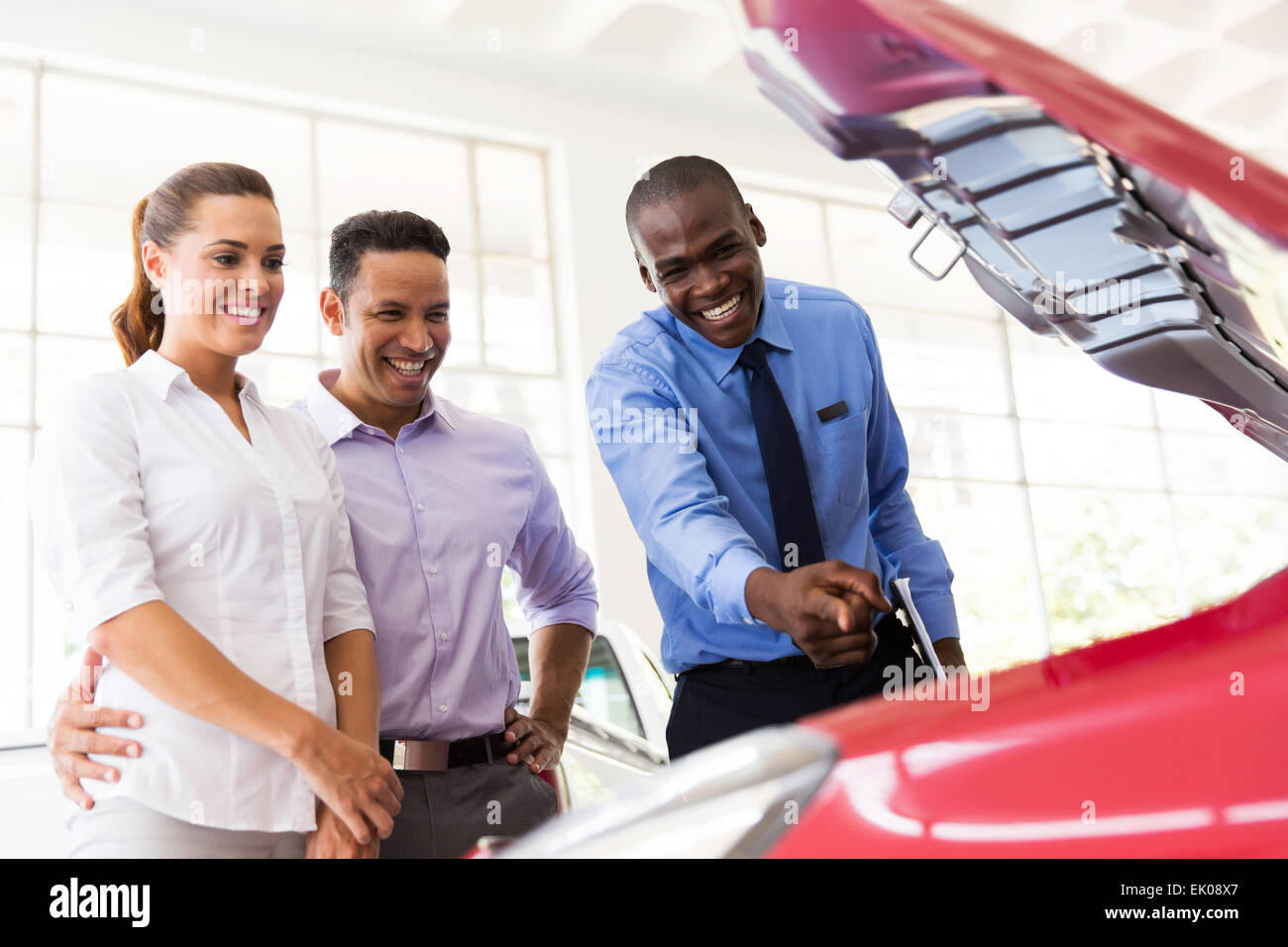happy African car salesman showing car engine to customers Stock Photo