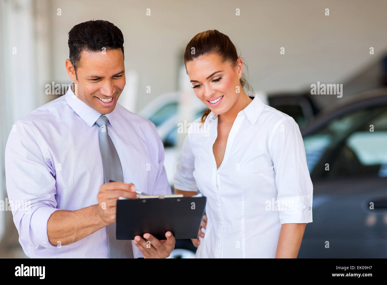 handsome vehicle dealership principal and saleswoman looking at