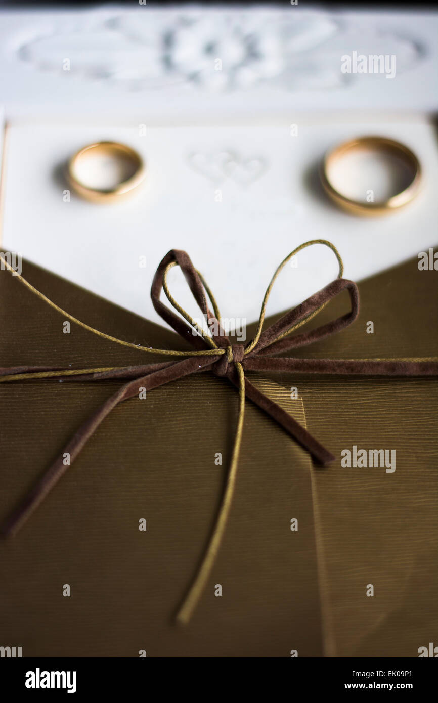 Wedding rings on the wedding invitation with focus on the bow Stock Photo