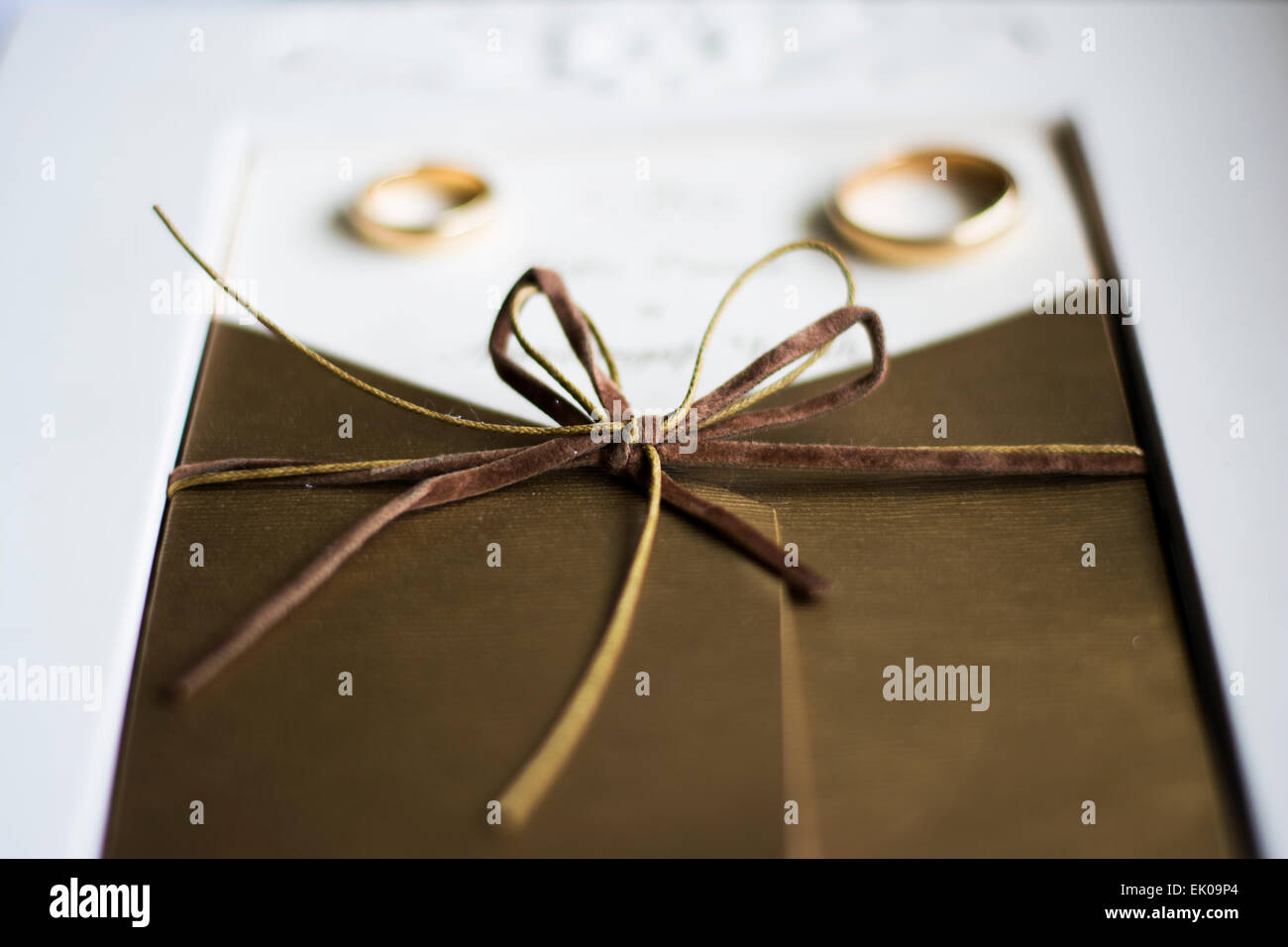 Wedding rings on the wedding invitation with focus on the bow Stock Photo