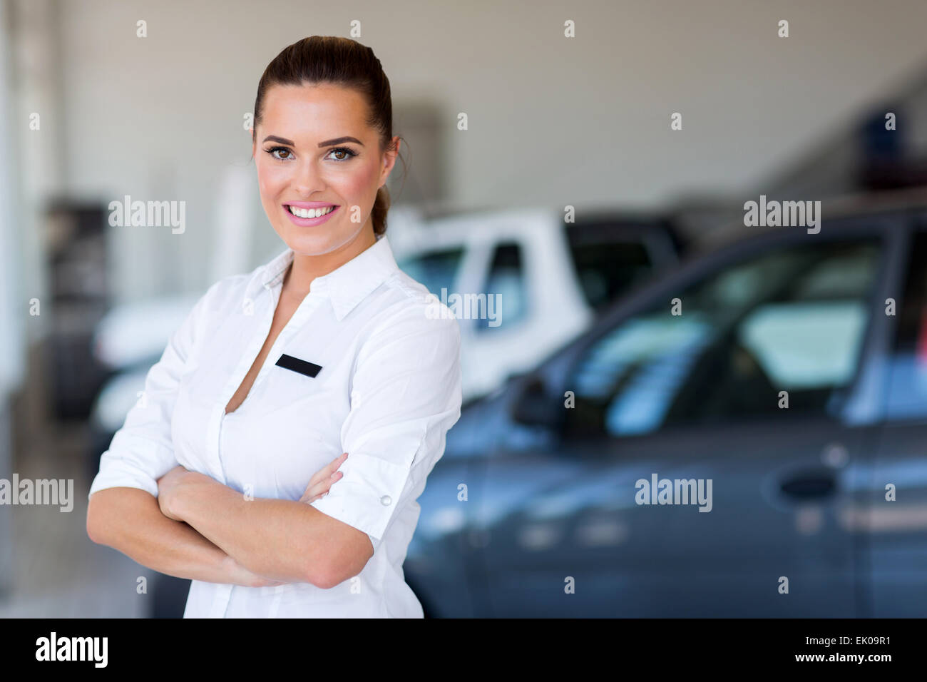 pretty female car dealer with arms crossed Stock Photo Alamy