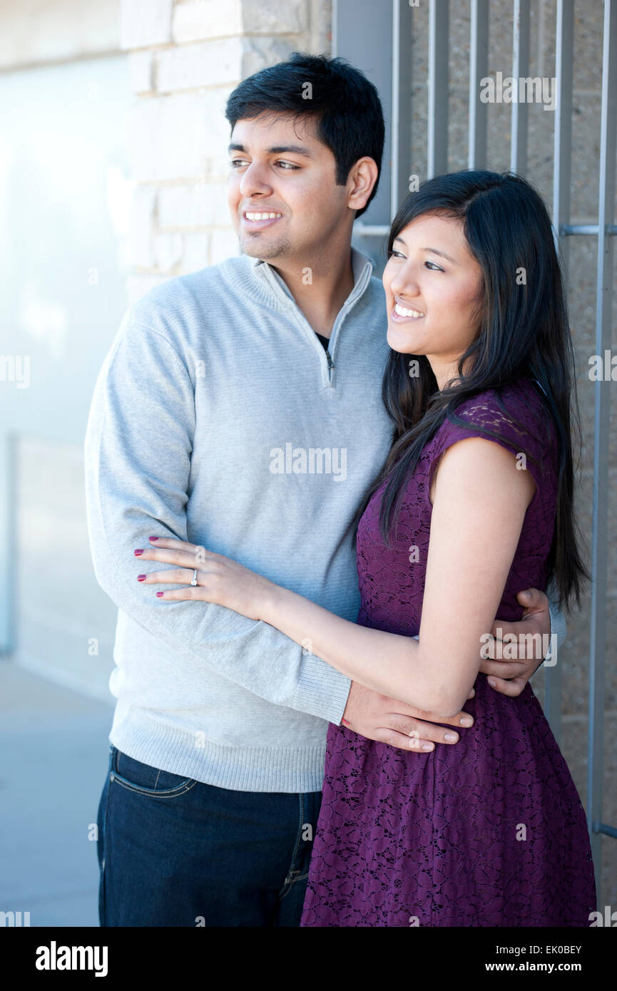 A young and happy Indian couple looking to the left on a sunny day ...