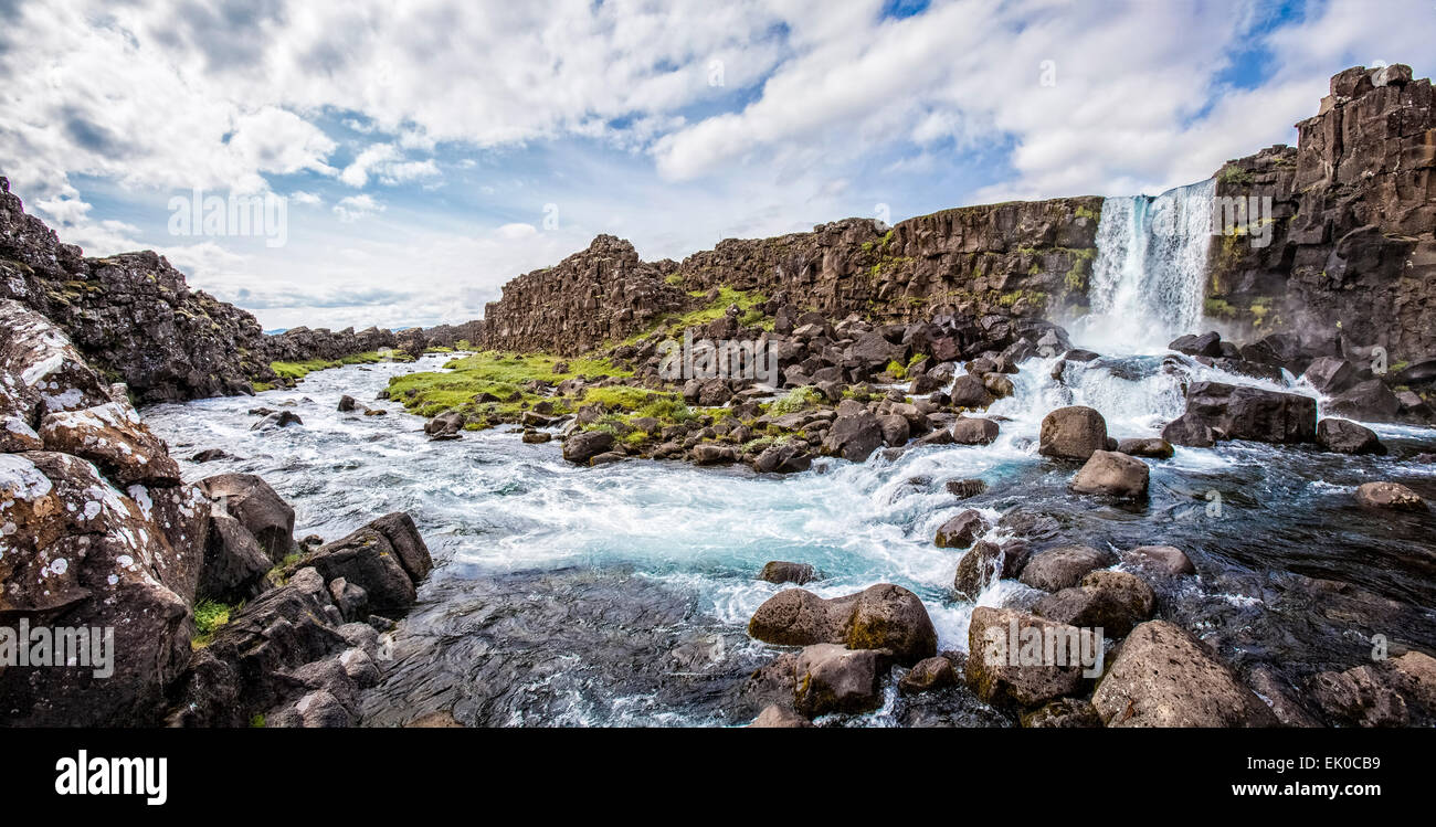 Waterfall flows over a cliff of lava rock formations in Thingvellir National Park Iceland. Stock Photo