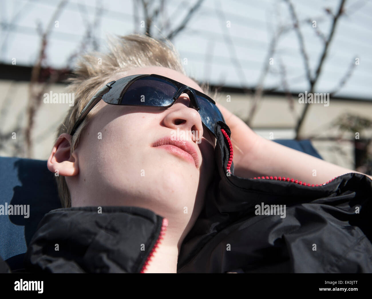 Male teenager enjoying the first warming sunbeams at springtime Stock Photo