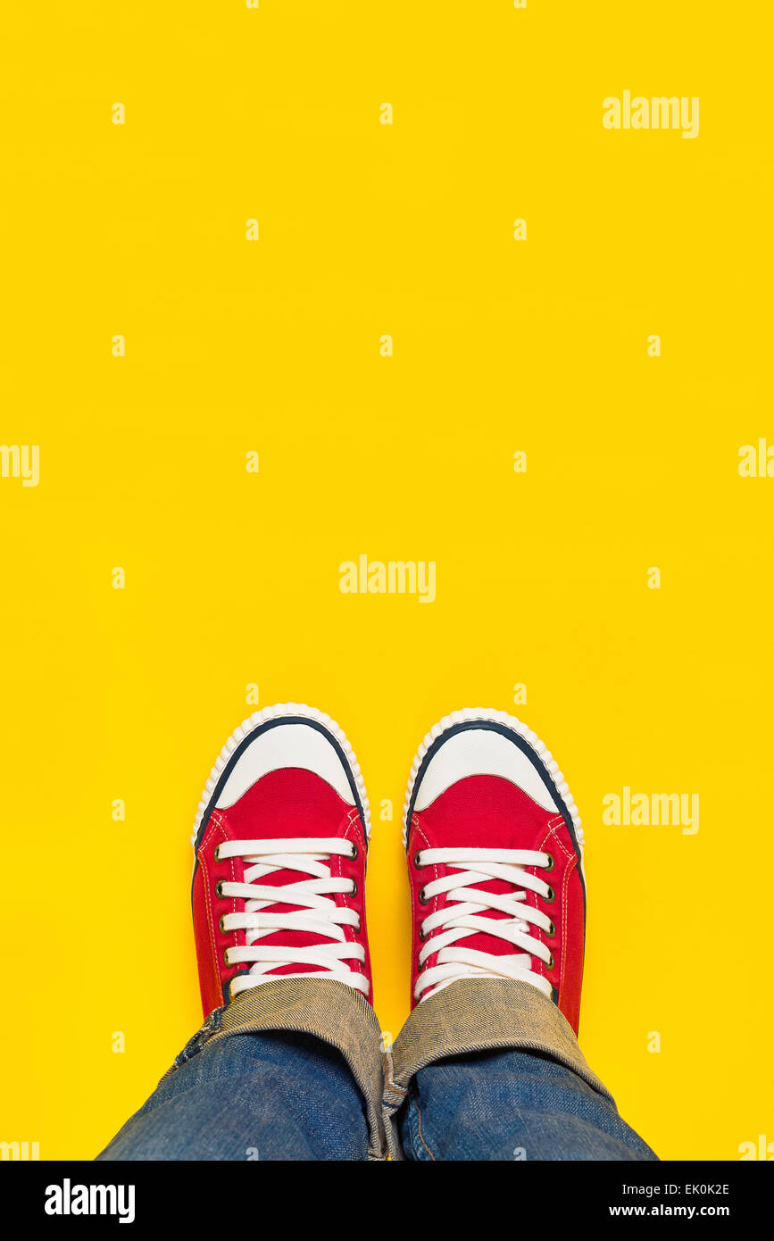 Feet From Above Concept, Teenage Person in Red Sneakers Standing on Yellow Background, B;lank Copy Space in Front. Stock Photo