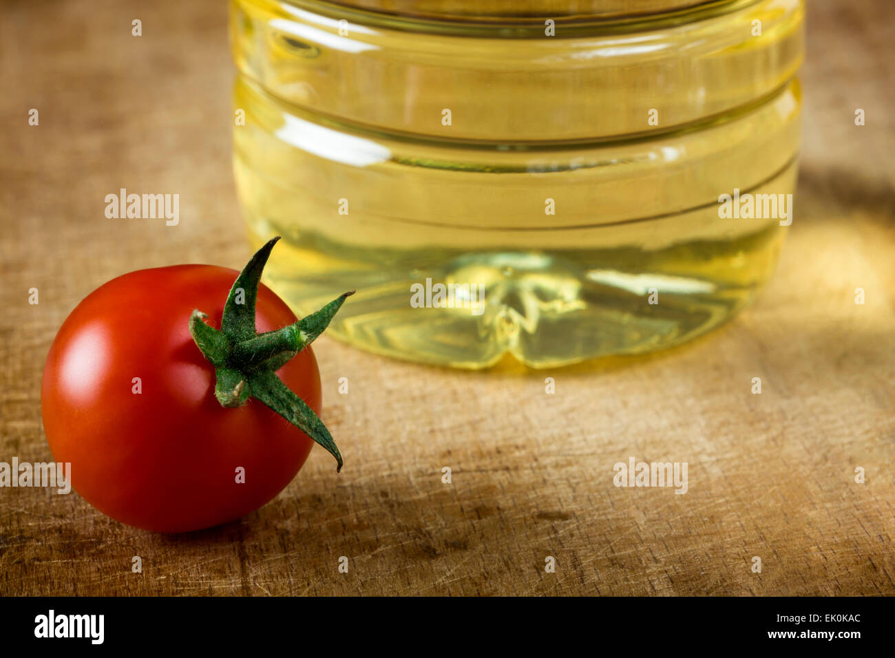 One red cherry tomato and oil on wood background surface Stock Photo