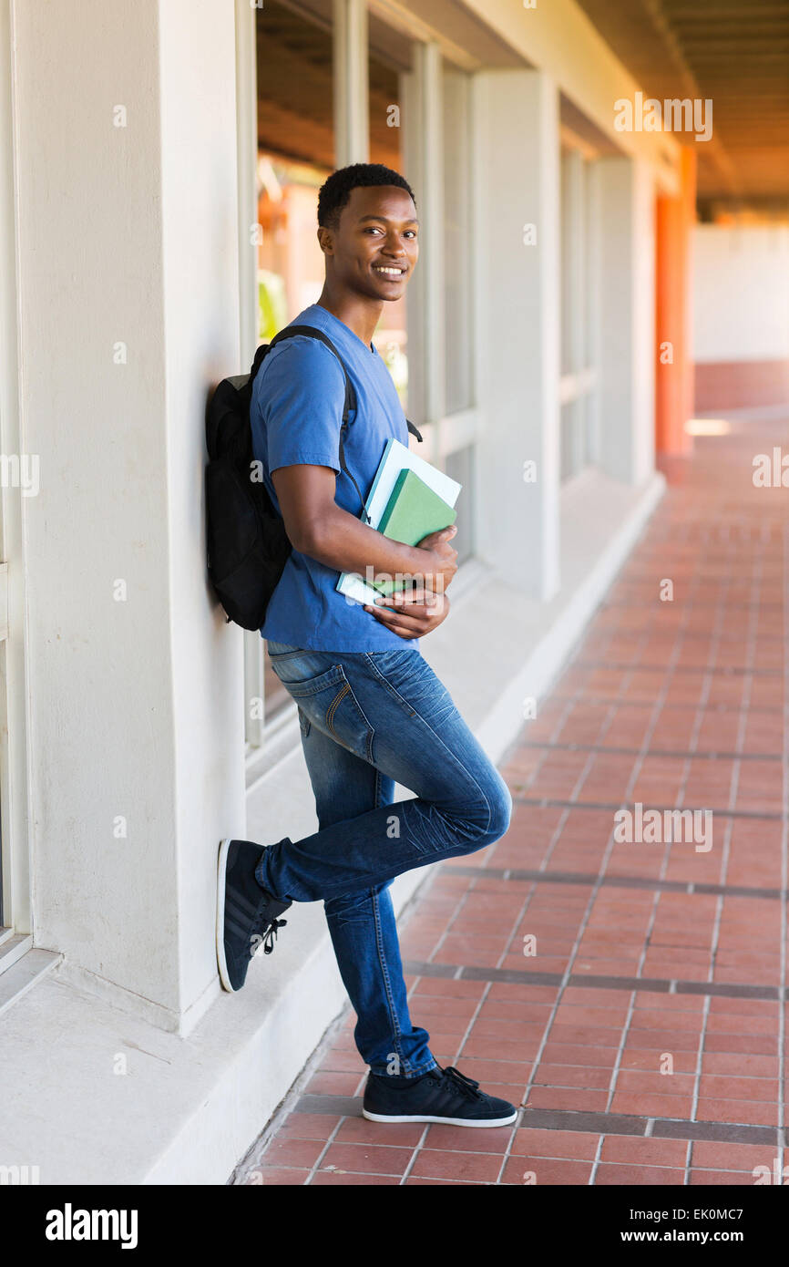 handsome African college student leaning against wall Stock Photo