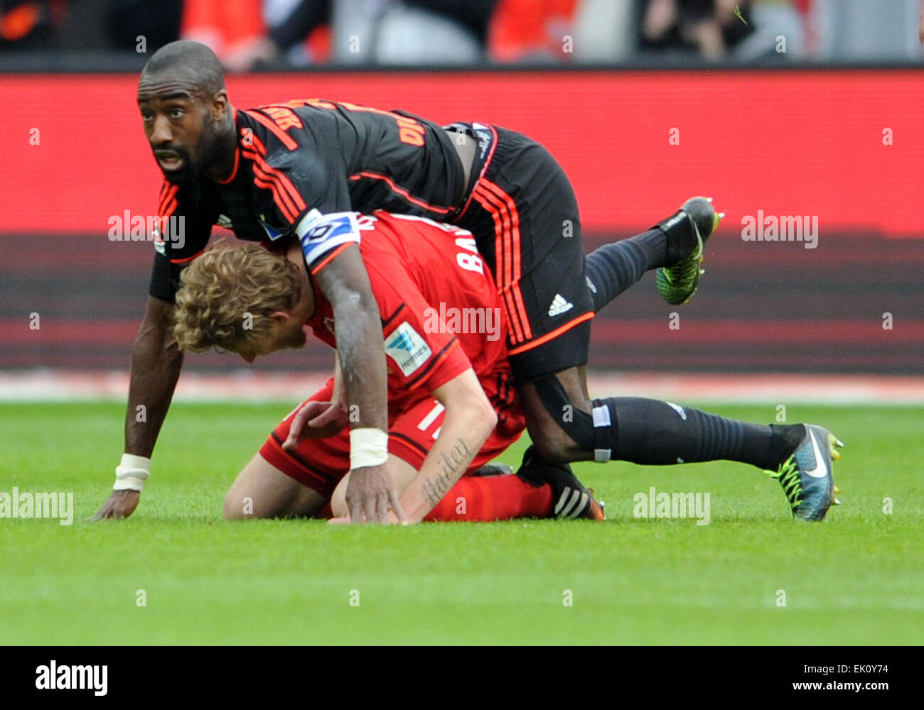 Leverkusen's Stefan Kiessling (bottom) and Hamburg's Johan Djourou fall after competing for the ball during the German Bundesliga soccer match between Bayer Leverkusen and Hamburger SV at the BayArena in Leverkusen, Germany, 4 April 2015. PHOTO: CAROLINE SEIDEL/dpa  (EMBARGO CONDITIONS - ATTENTION: Due to the accreditation guidelines, the DFL only permits the publication and utilisation of up to 15 pictures per match on the internet and in online media during the match.) Stock Photo