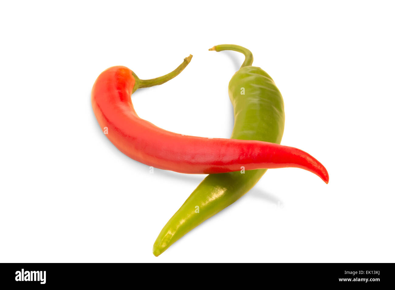 A whole red chili on top of a whole green chili (Capsicum annuum) isolated on white background Stock Photo