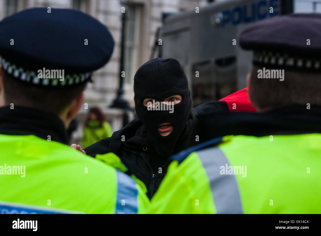 Whitehall, London, April 4th 2015. As PEGIDA UK holds a poorly attended rally on Whitehall, scores of police are called in to contain counter protesters from various London anti-fascist movements. PICTURED: A masked anti-fascist counter-protester taunts police officers Credit:  Paul Davey/Alamy Live News Stock Photo