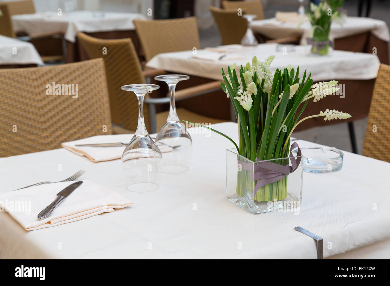 A closeup to part of a table at a restaurant in venice, showing, tablewear, glasses, chairs and flowers Stock Photo