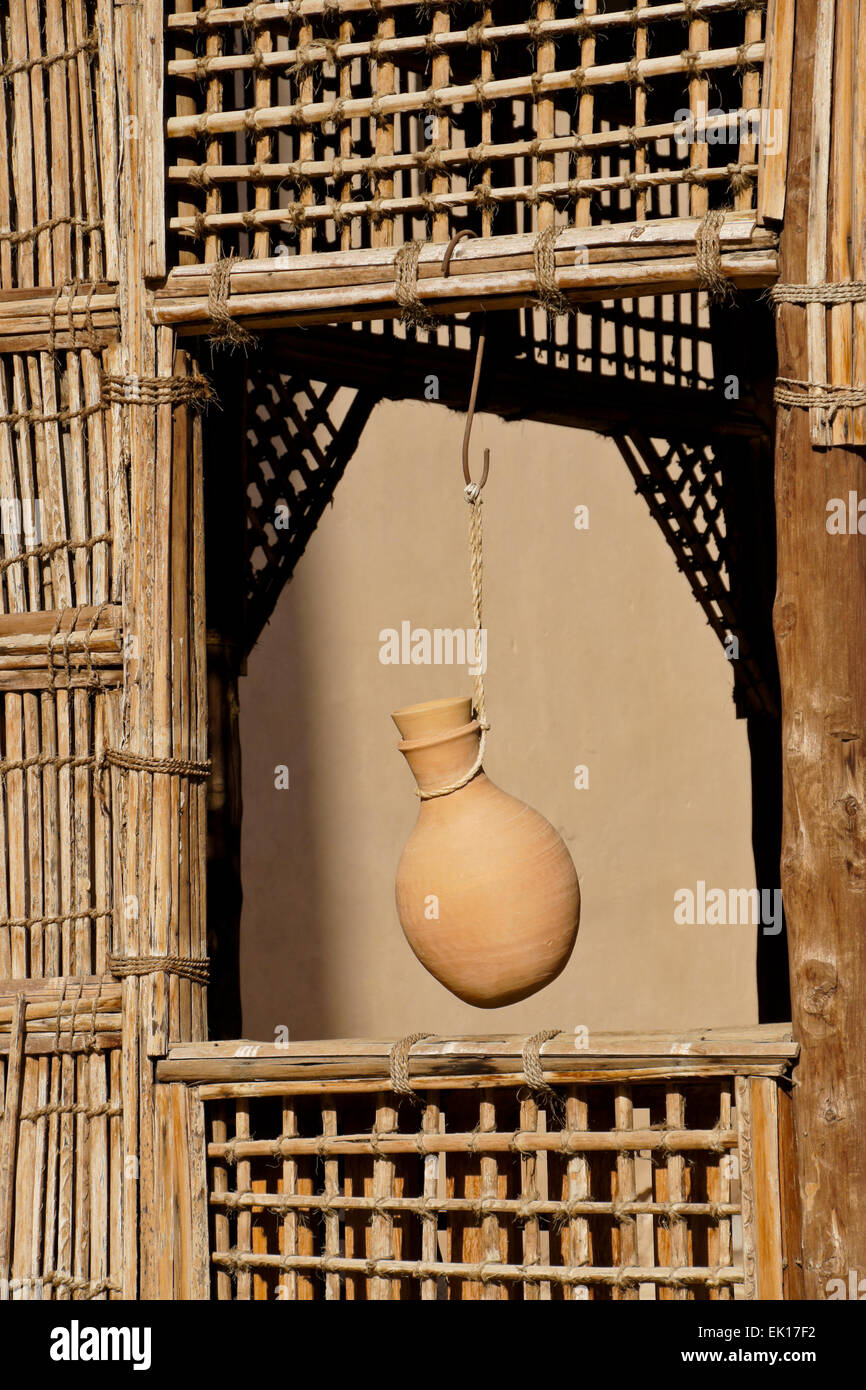 Pottery water jug hanging in window of latticed wood shelter, Nizwa Fort, Nizwa, Oman Stock Photo