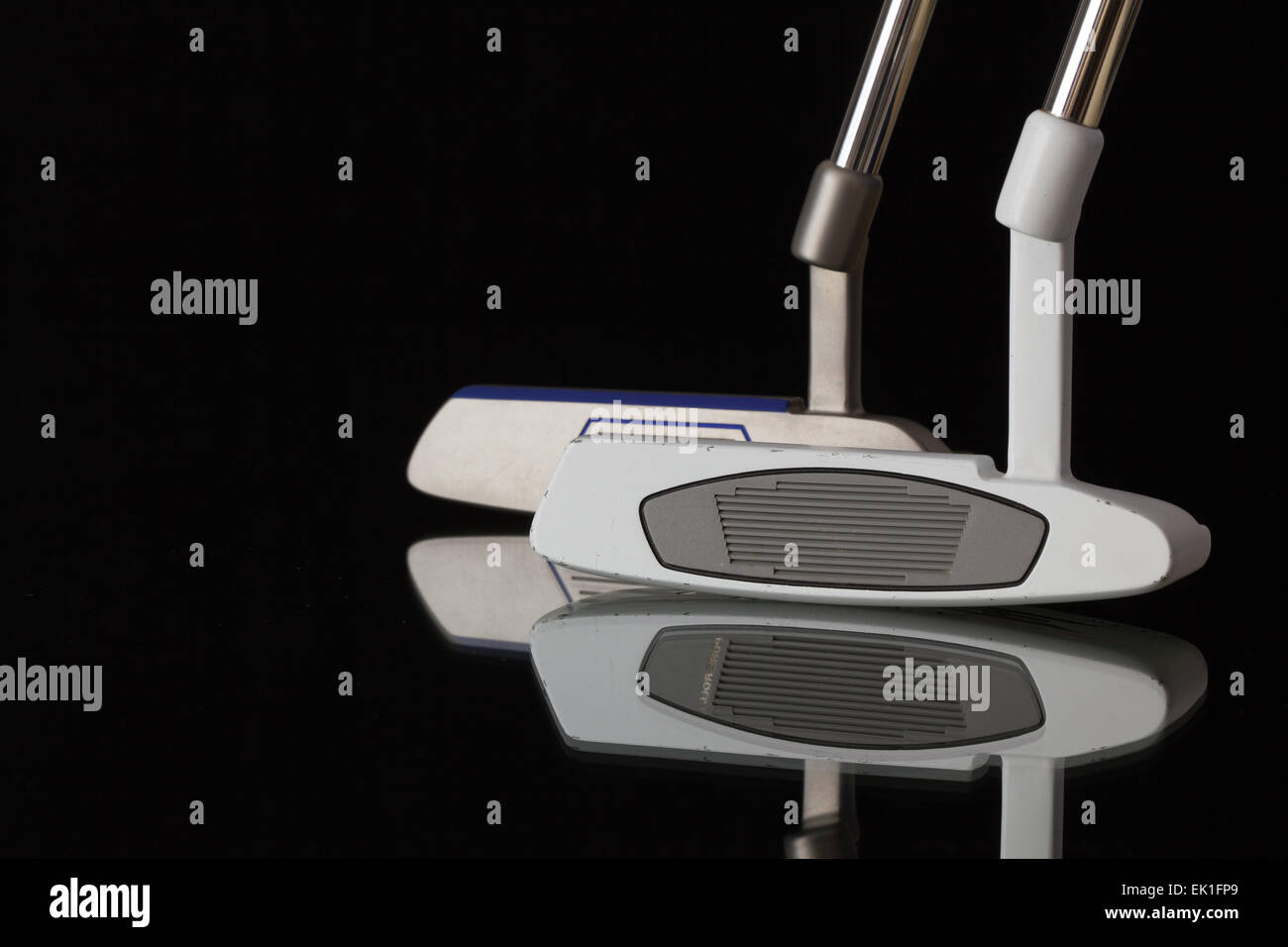 Two different golf putters on a black glass desk Stock Photo Alamy