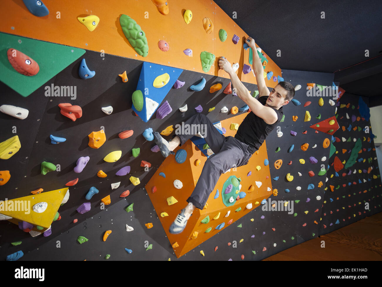 Young man practicing bouldering in indoor climbing gym Stock Photo
