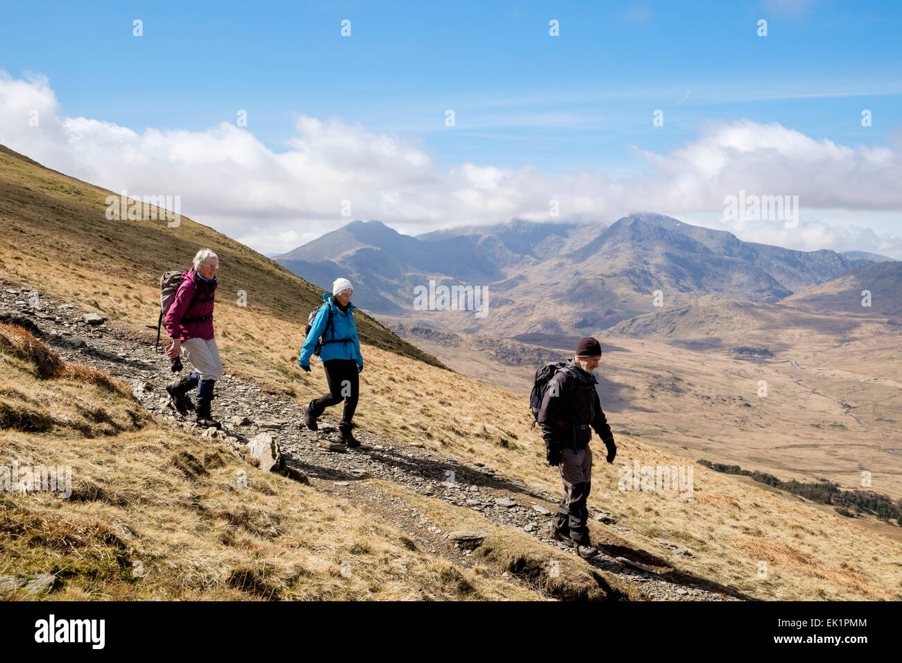 Hikers hiking down on mountain path from Moel Siabod to Capel Curig with view to Mt Snowdon Horseshoe in mountains of Snowdonia (Eryri) Wales UK Stock Photo