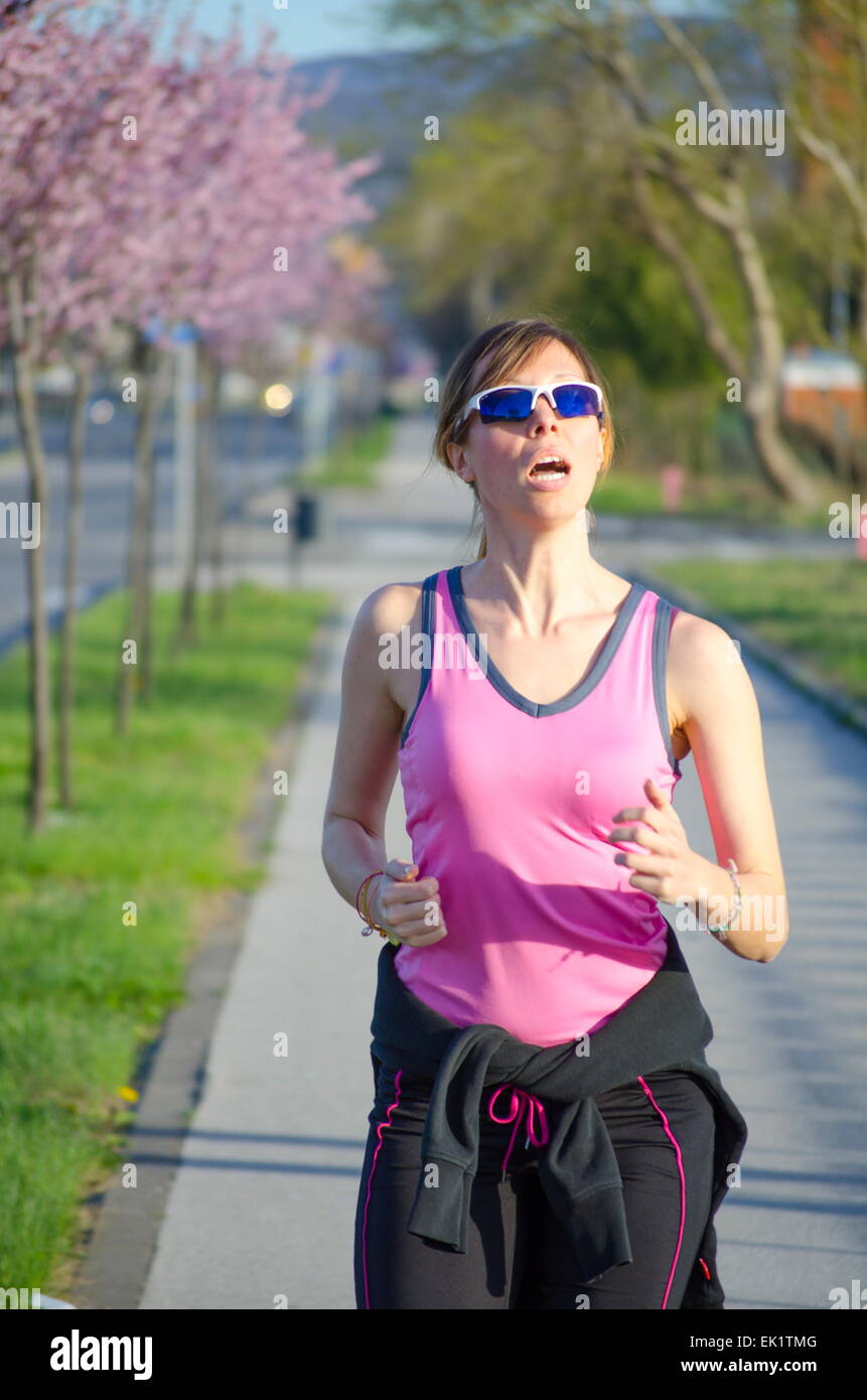 Young girl in a pink shirt jogging   on a sunny spring day Stock Photo