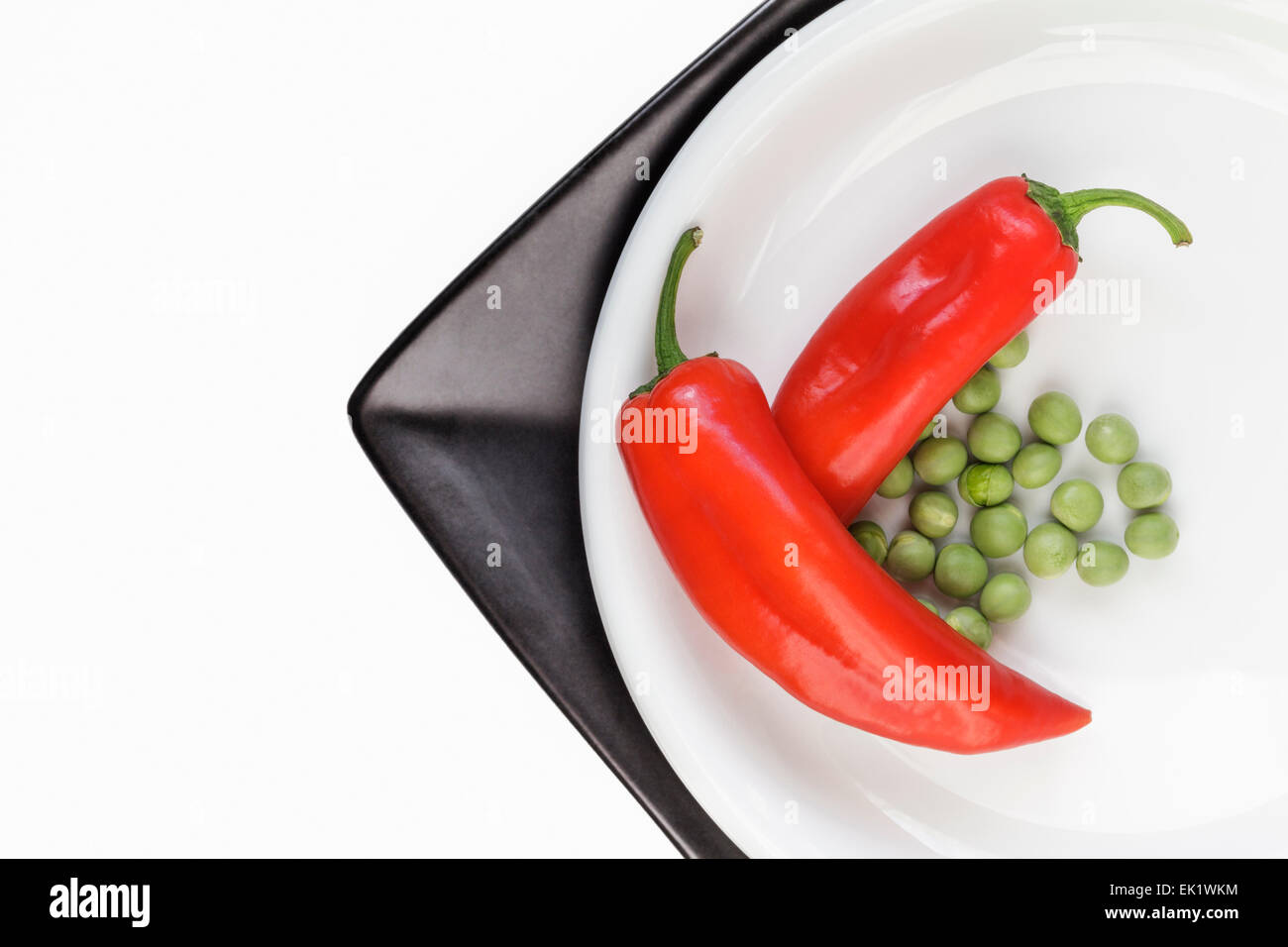 Red Peppers and Peas on white and black Plate Stock Photo