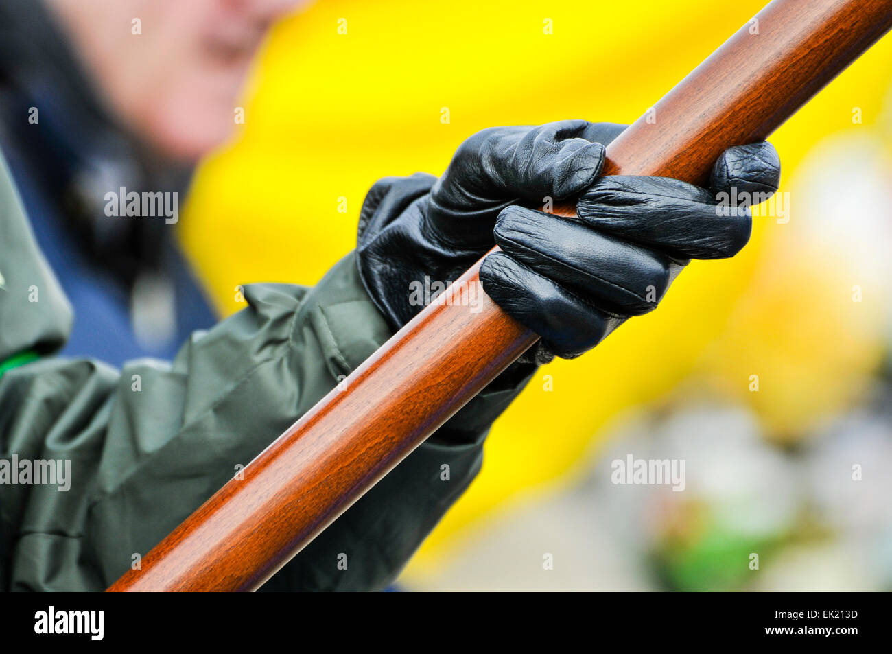 A person wearing a paramilitary style uniform with black gloves, holds a flag pole at an Irish Republican commemoration. Stock Photo
