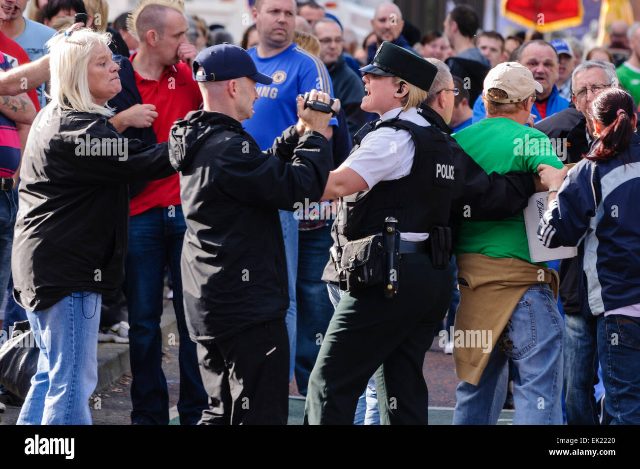 PSNI Police woman shouts at people in an attempt to hold back a large, hostile crowd Stock Photo