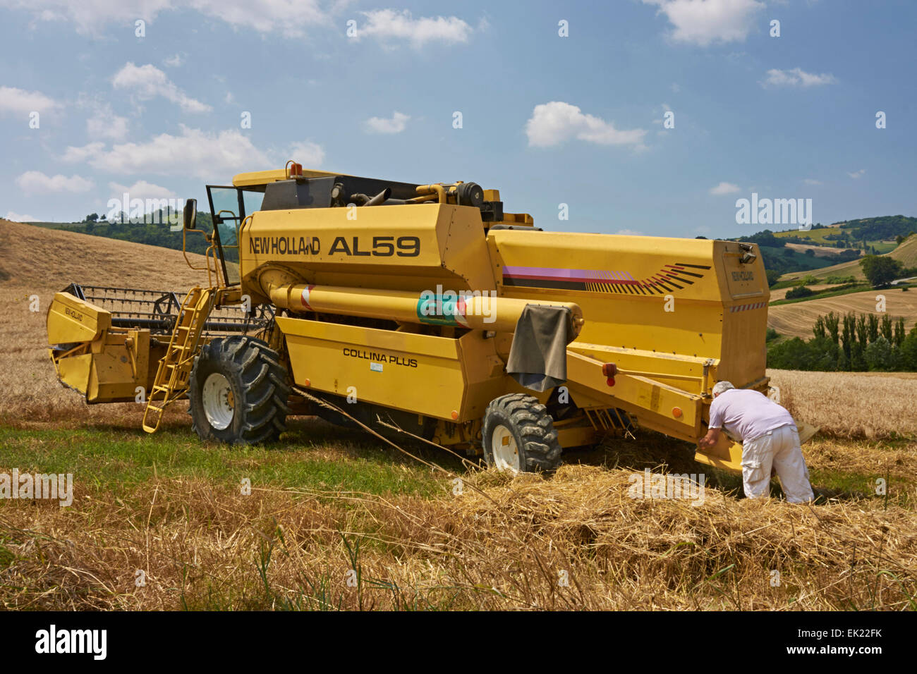 Modern combined harvester at work on slopes of hilly fields Stock Photo