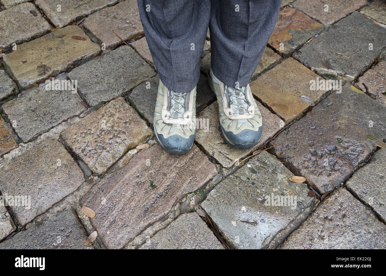 Feet in walking boots standing on cobbled stones in Rainy day in Barcelona Stock Photo