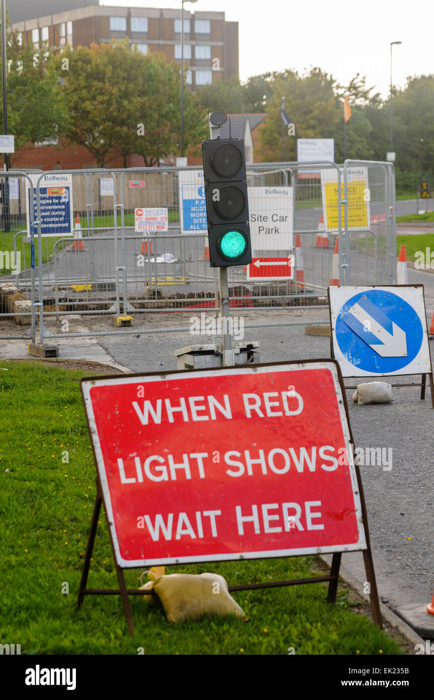 Roadworks with green traffic lights and a sign saying "When red light shows wait here Stock