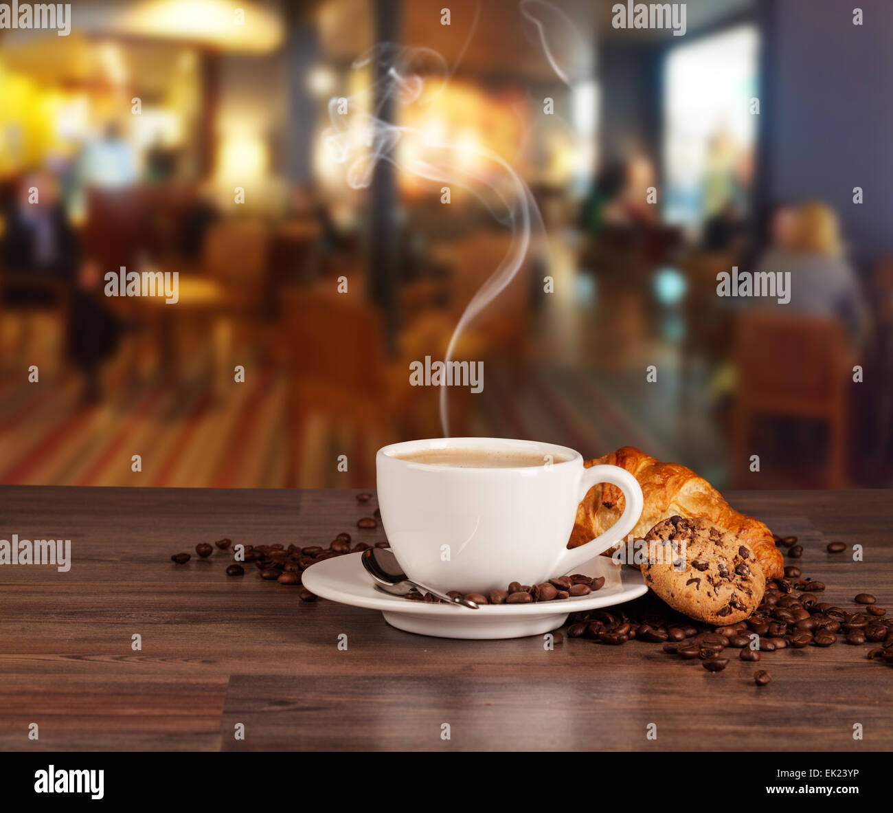 Coffee drink served with croissant on wooden table with blur cafeteria as background Stock Photo