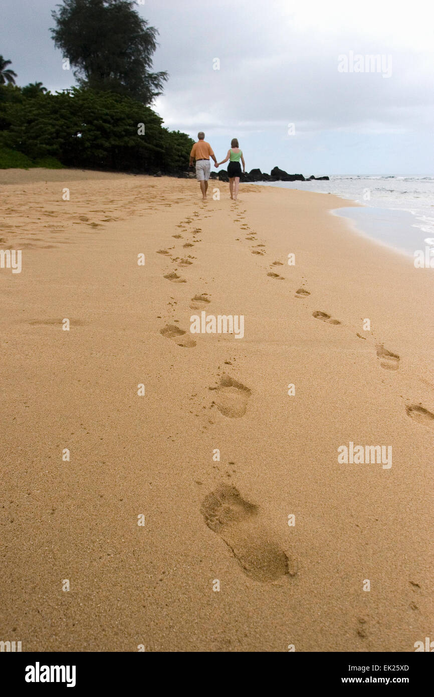 A couple go for a romantic walk in Poipu beach, Kauai, Hawai. Stock Photo