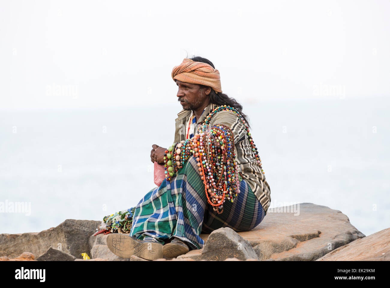 Local man sitting on rocks selling necklaces, beads and trinkets as ...